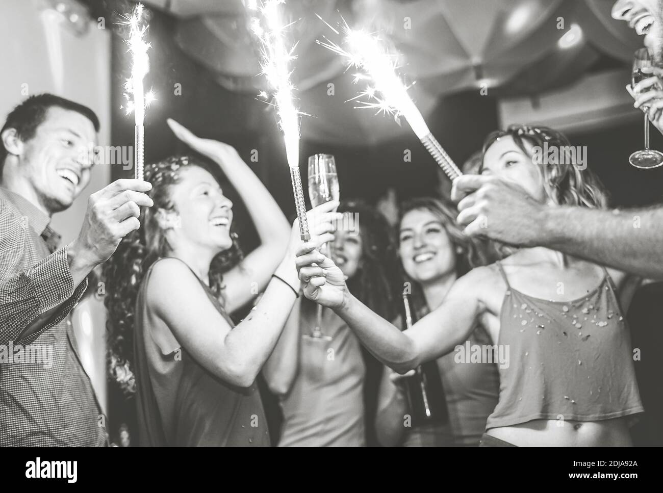 Happy friends doing party dancing and drinking champagne at nightclub - Millennial young people having fun with sparklers fireworks in discoclub Stock Photo