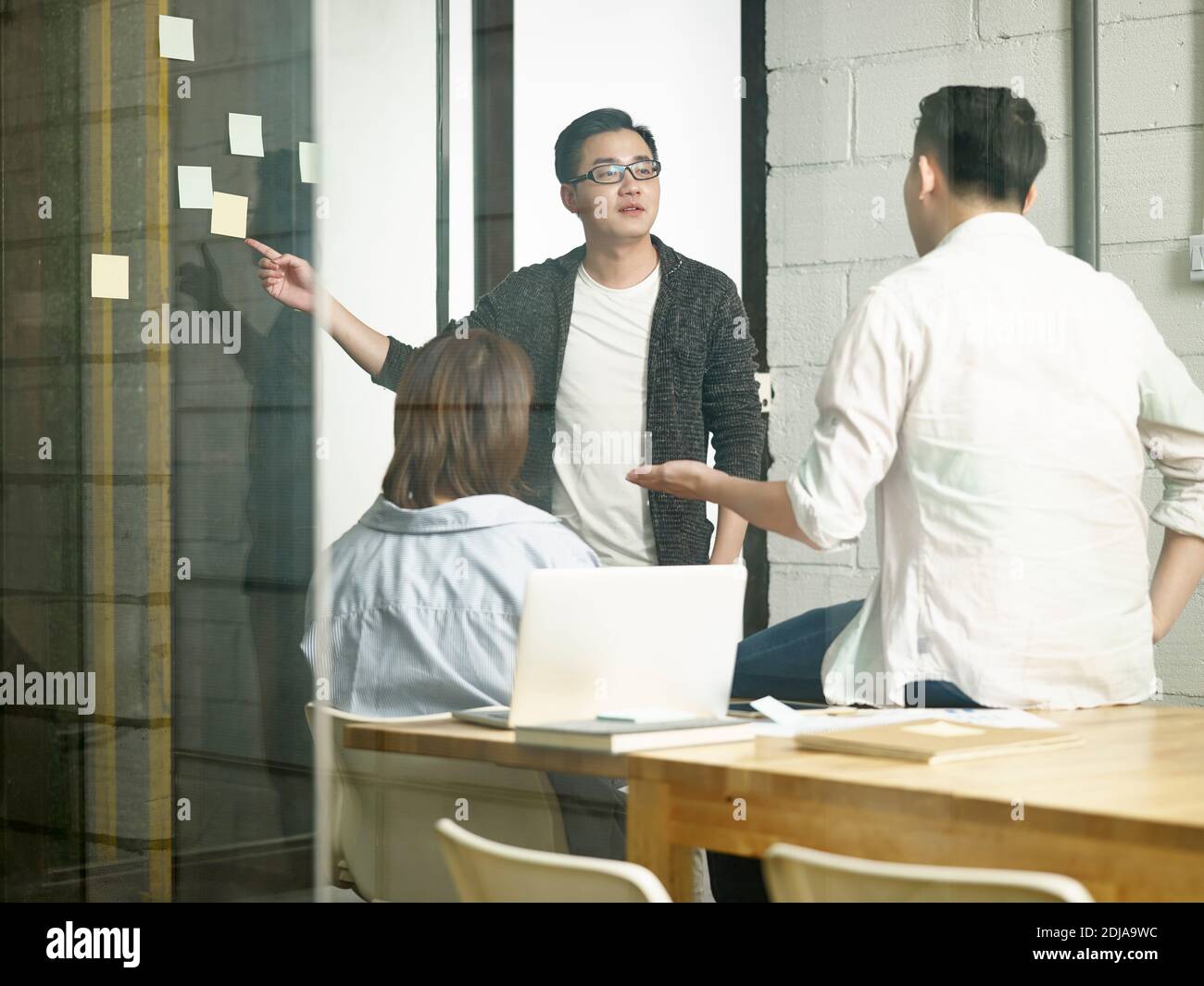 three young asian entrepreneurs meeting in office discussing business Stock Photo