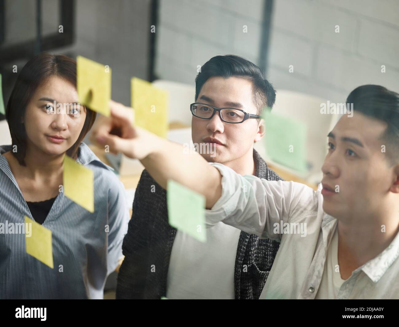 three young asian entrepreneurs meeting in office discussing business Stock Photo