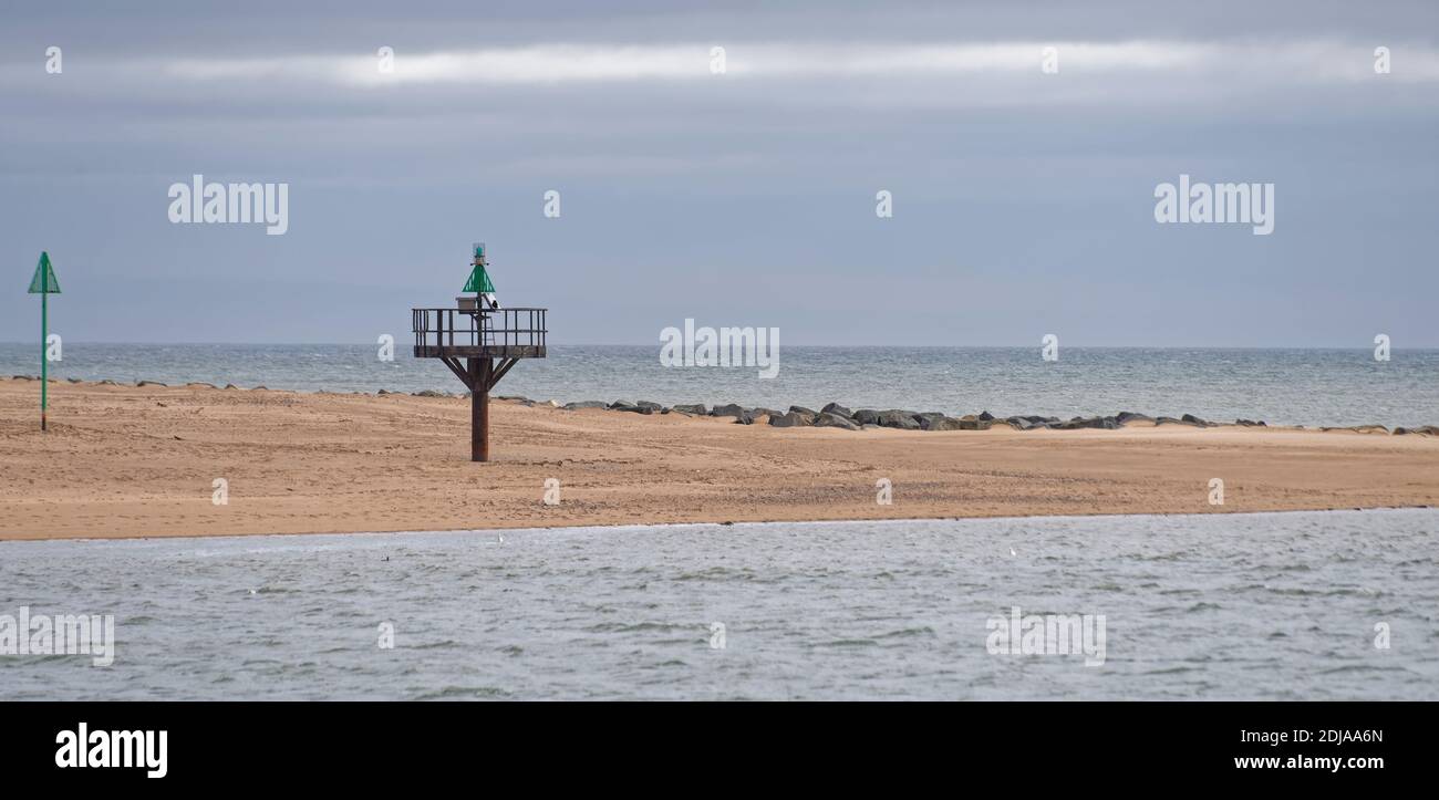 The Green Navigational Buoys and Markers at the North side of the Port of Montrose on the spit of sandy beach at high tide. Stock Photo