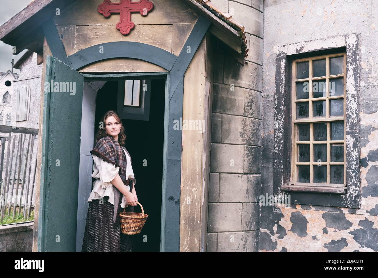 Woman in retro dress in the courtyard of an old Church with a cross ...