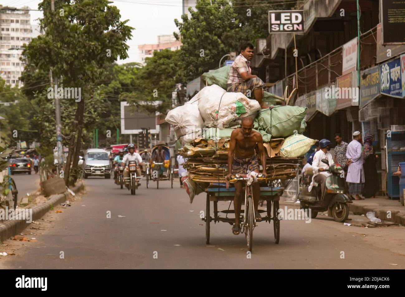 Dhaka, Bangladesh - October 30, 2018: A cart driver with a huge shipment and with a man on the top Stock Photo