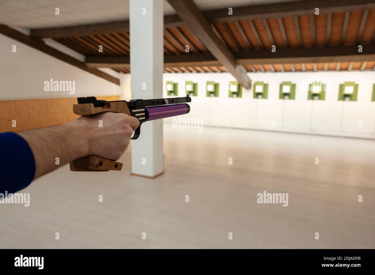 Shooter with professional air gun, during training at the firing range. Electronic target system. Stock Photo