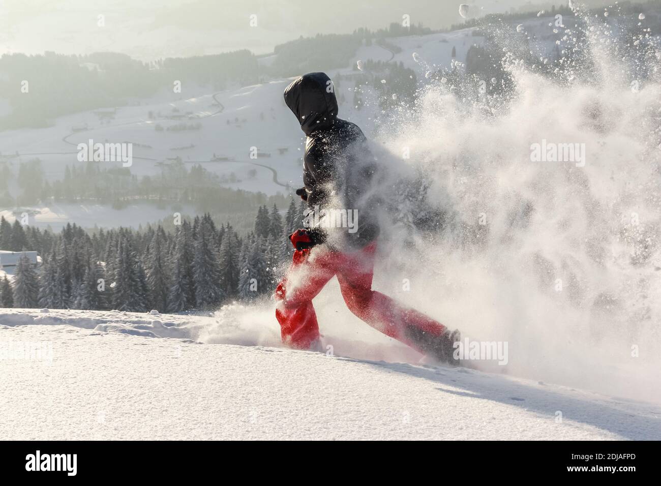 Happy Man with hood running in deep powder snow with snowshoes. Snow is
