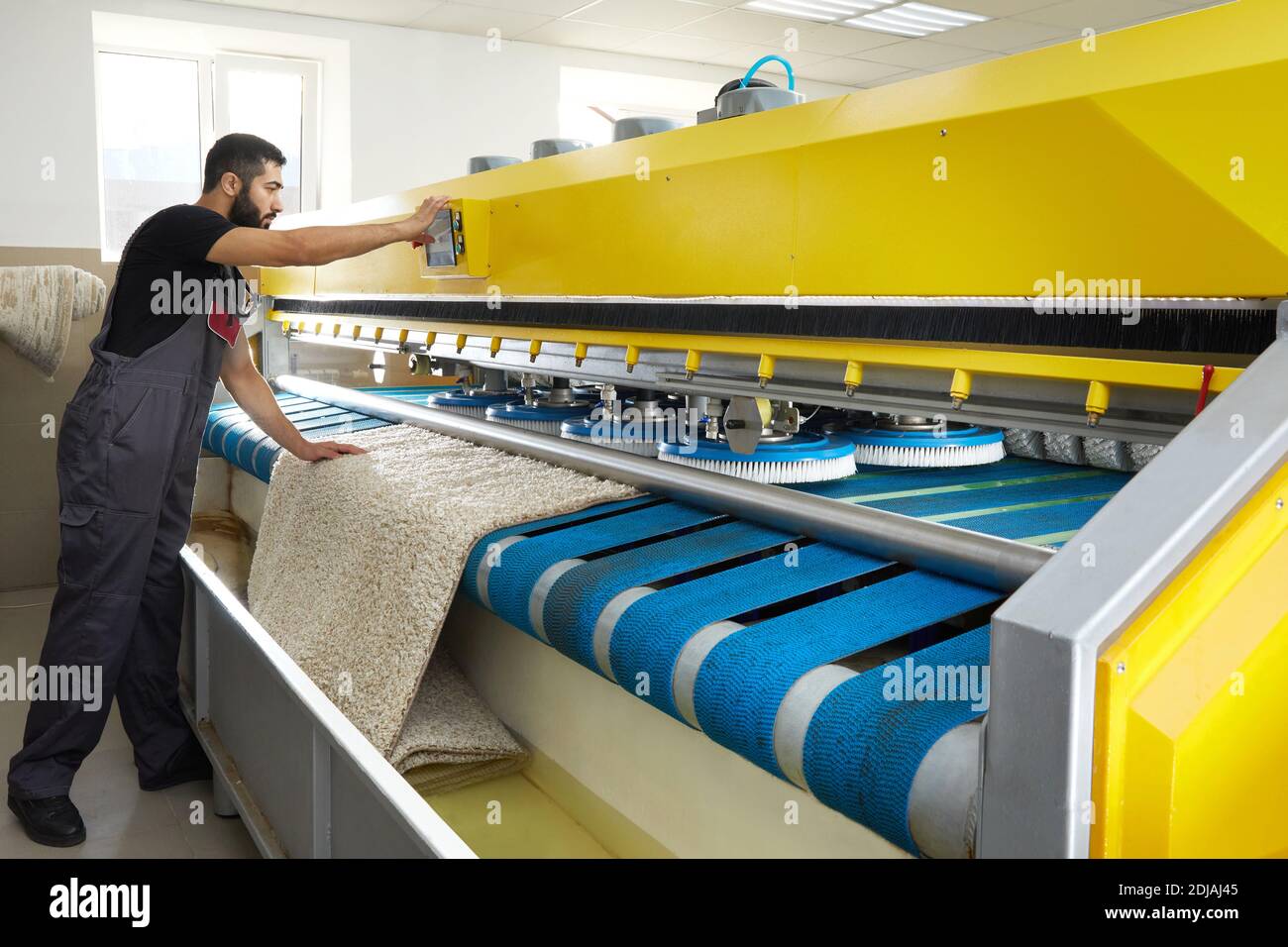 Man operating carpet automatic washing machine in professional laundry service Stock Photo