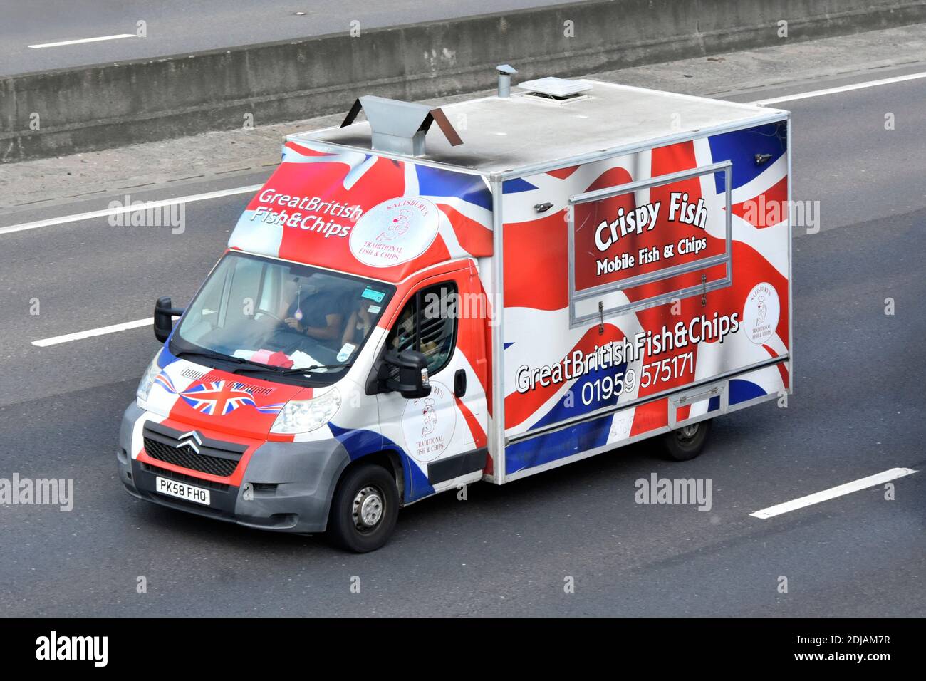Mobile crispy great British fish and chips with colourful union jack graphics design on side of Citreon van & driver driving along UK motorway road Stock Photo