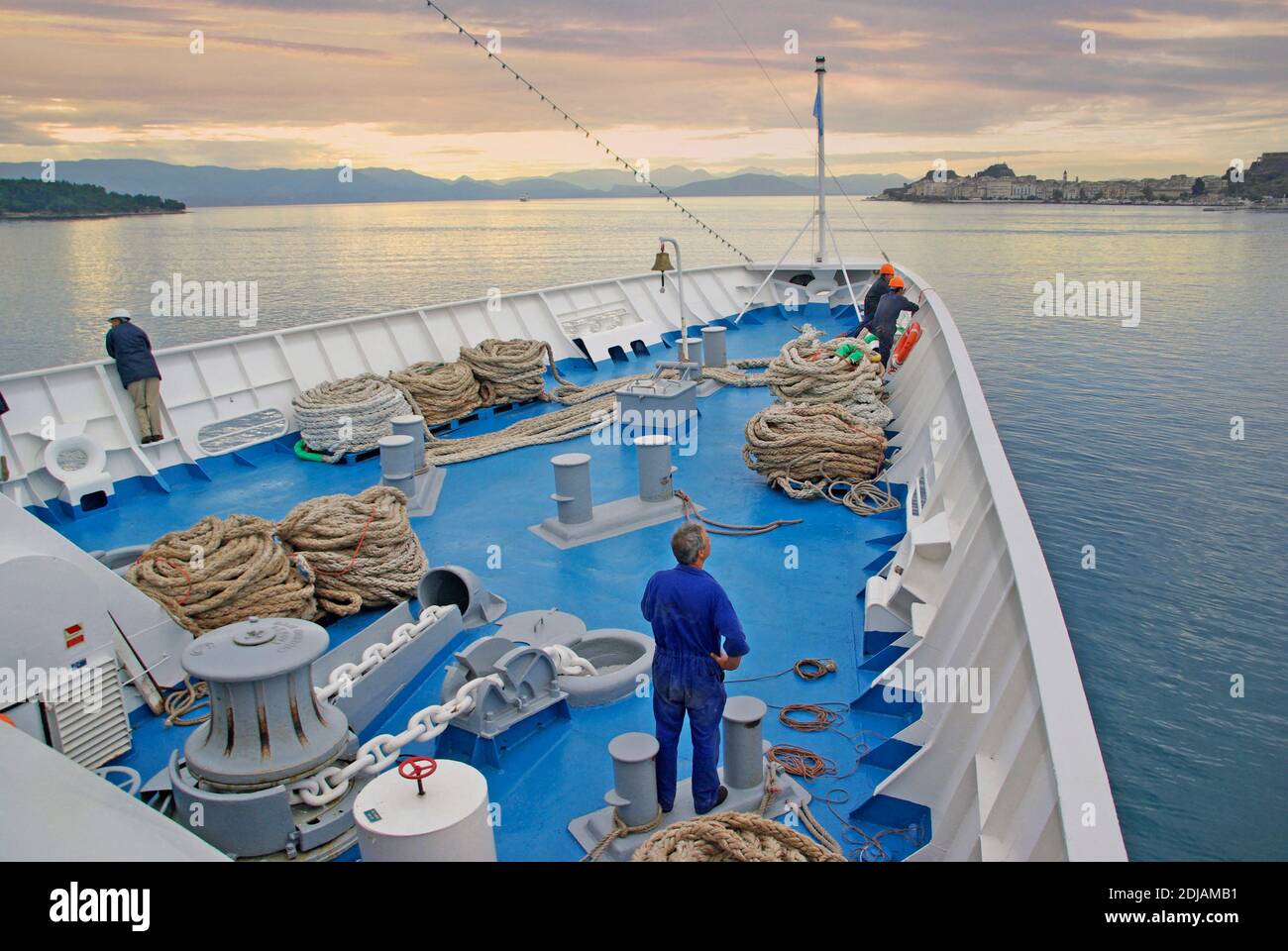 Merchant Navy sailor & seafarers working bow of cruise ship liner deck crew standby to throw mooring rope overboard at port jetty Greek island Corfu Stock Photo