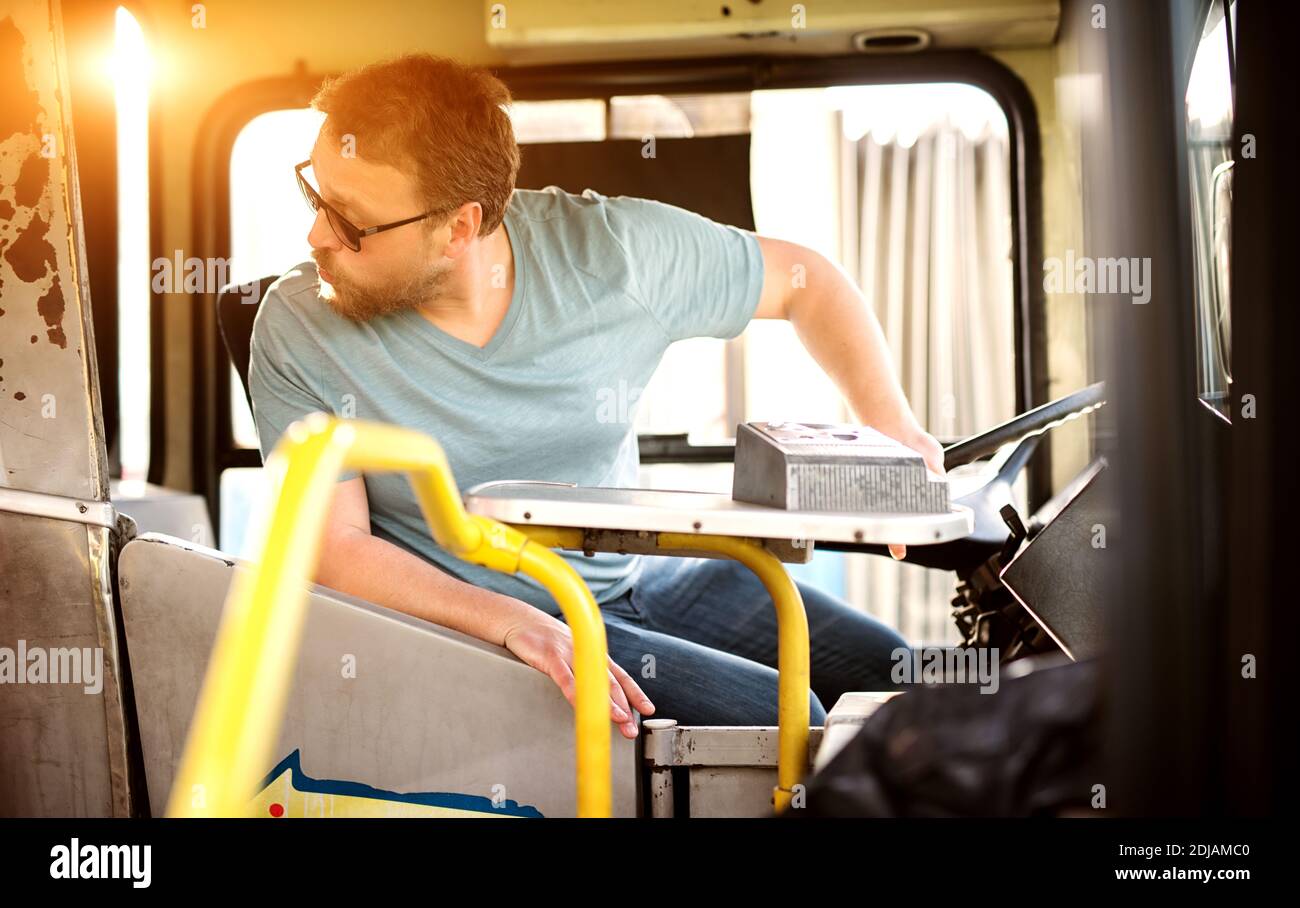 Male young bus driver is checking if his passengers are sitting in