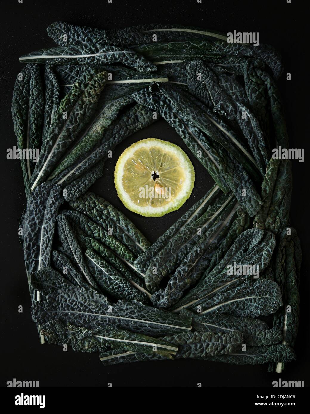 Green Tuskan Kale leaves end lemon slices on a dark background. Healthy detox vegetables . Clean eating and dieting concept. Top view. Health kale ben Stock Photo