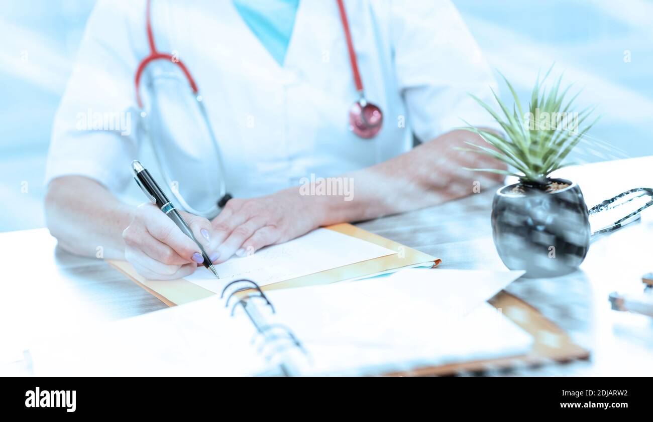 Female doctor writing a medical prescription in office; light effect ...