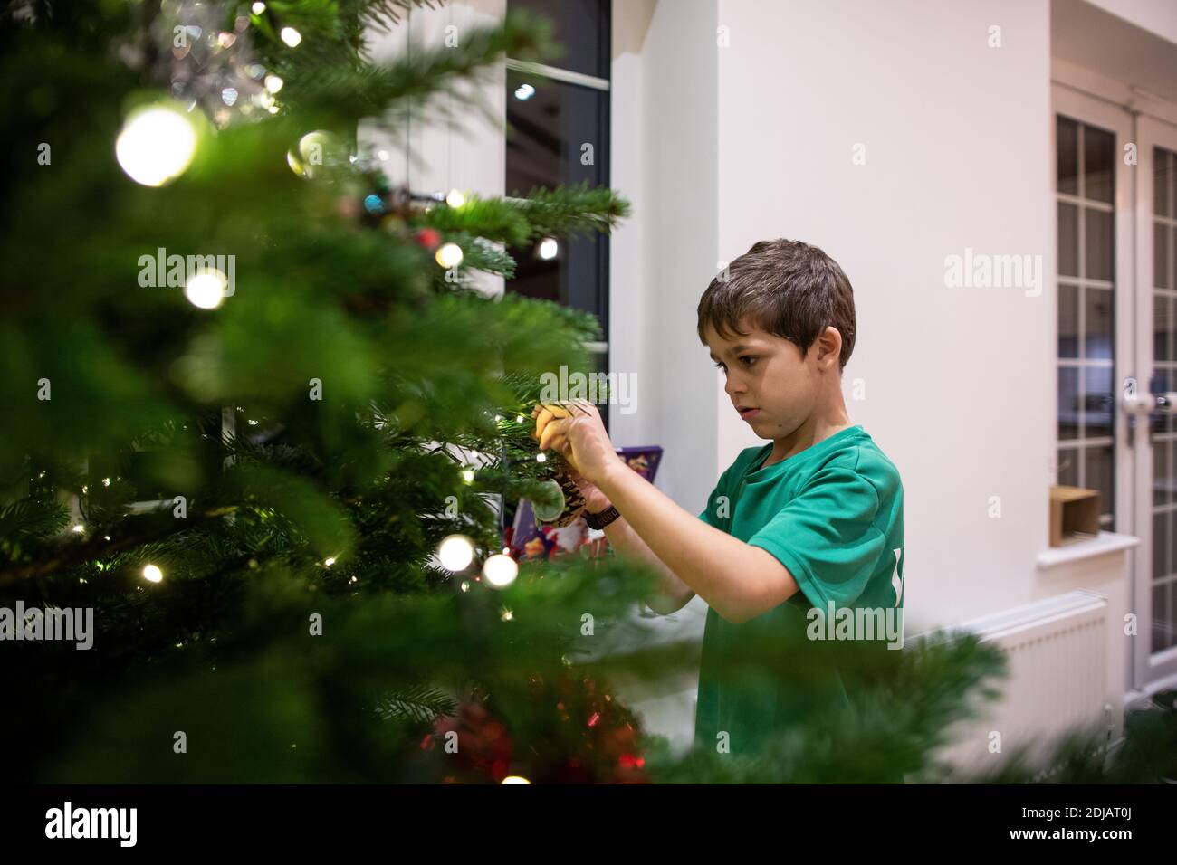 Family at home decorating their Christmas tree ahead of the Xmas
