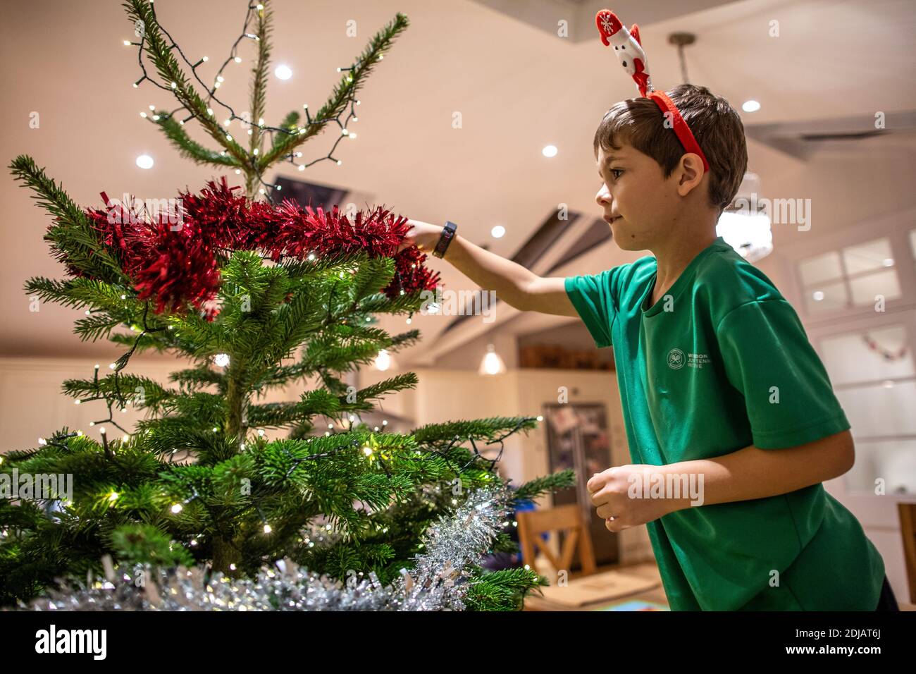 Family at home decorating their Christmas tree ahead of the Xmas