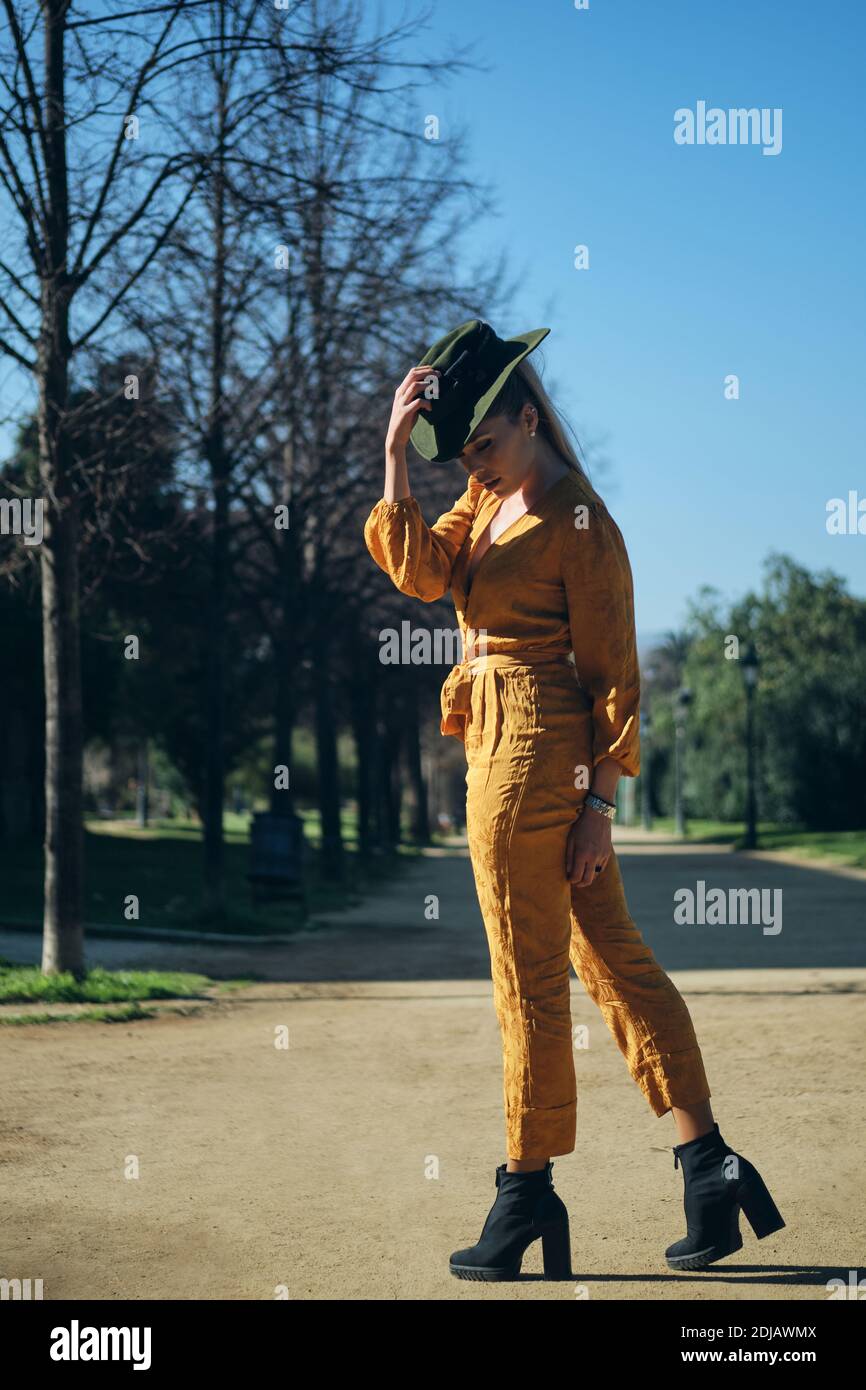 Young gorgeous woman in bright overalls wearing hat sensually posing on ...