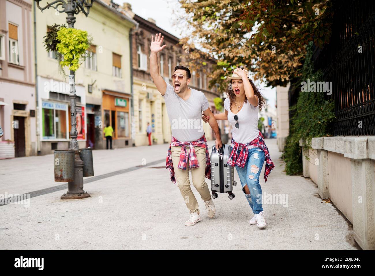 Young excited couple is running and waving to someone rushing to get on ...