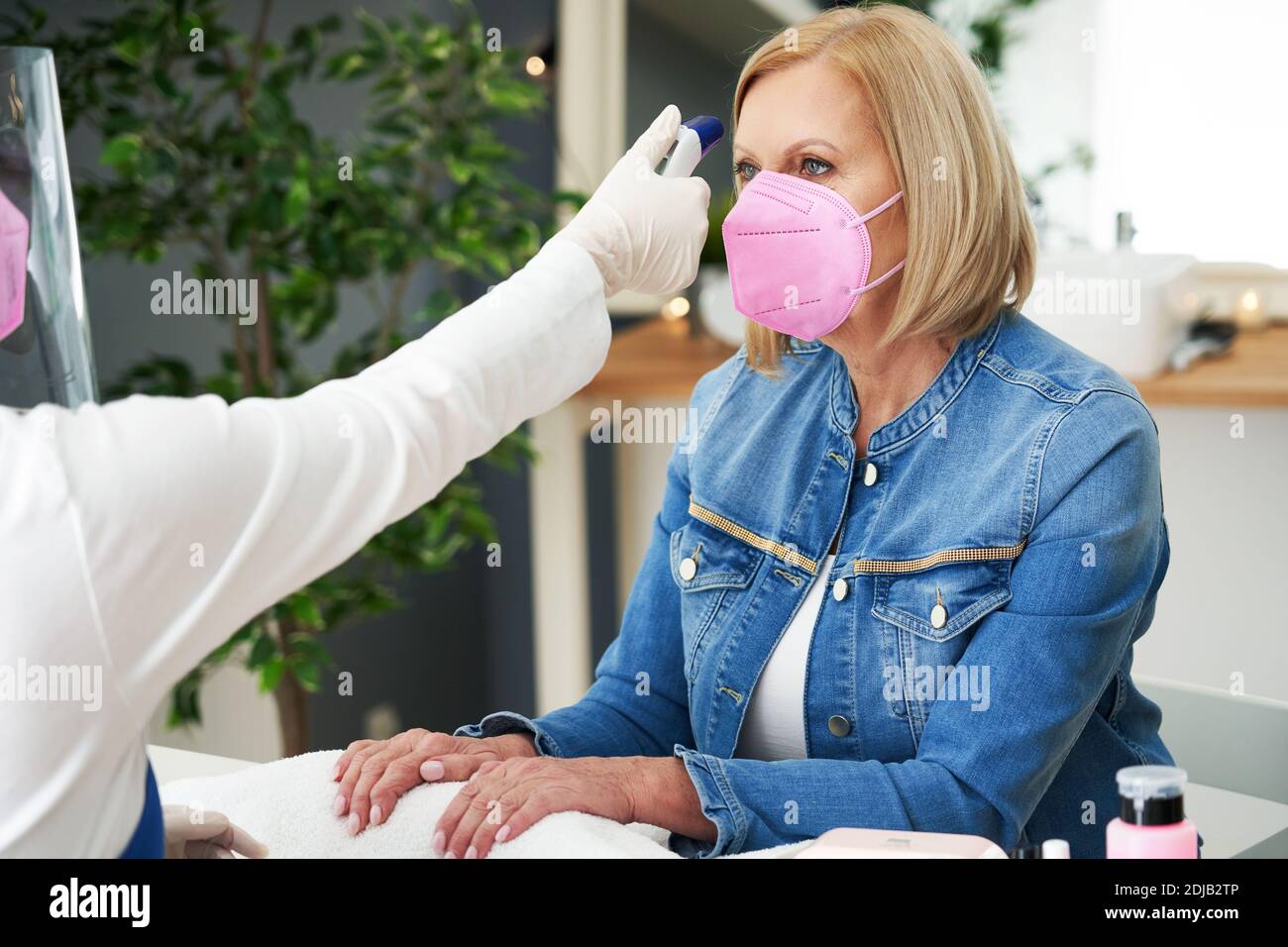 Senior lady wearing a mask in manicure salon Stock Photo