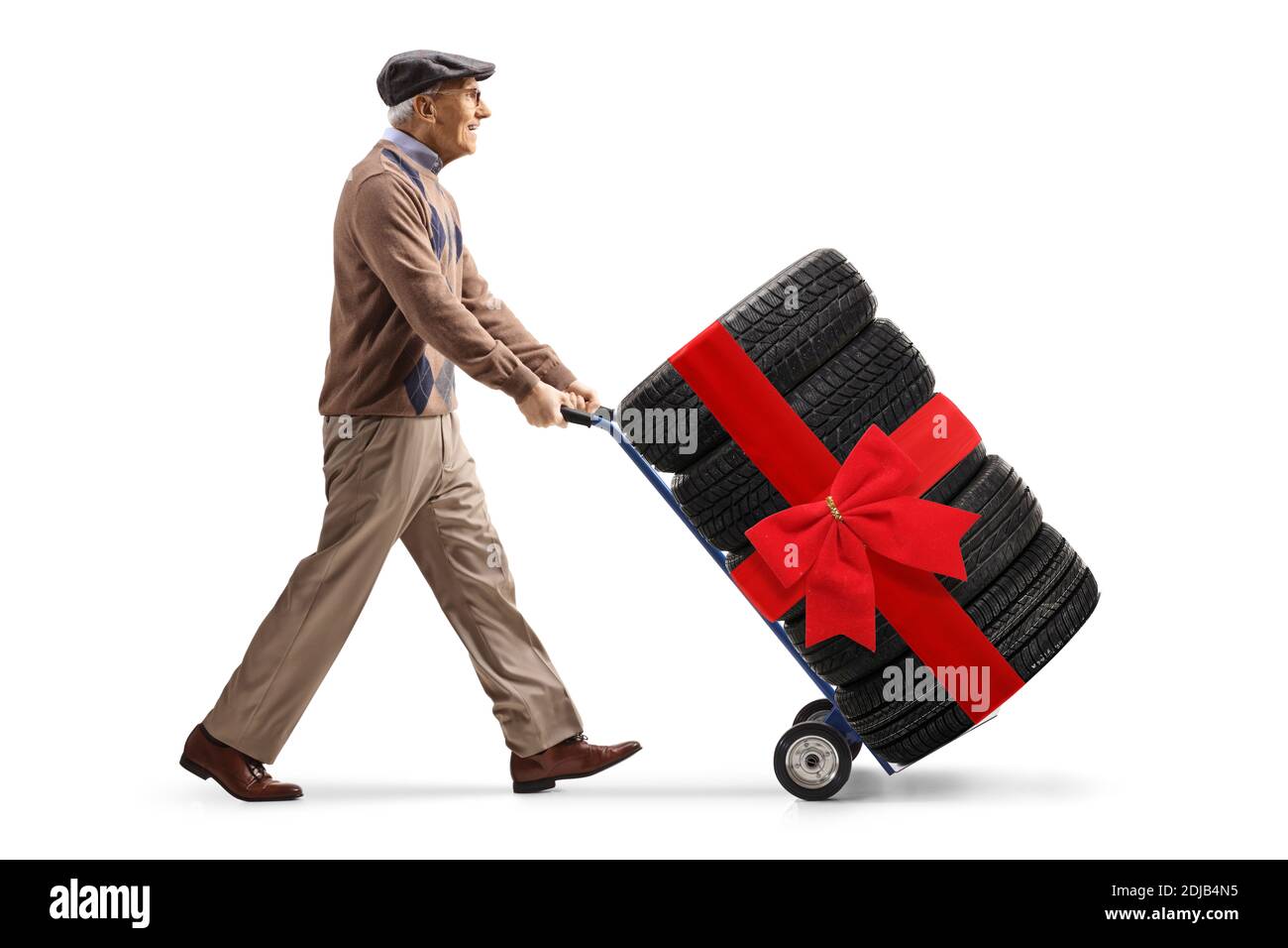 Full length profile shot of an elderly man pushing car tires with a red bow on a hand truck isolated on white background Stock Photo