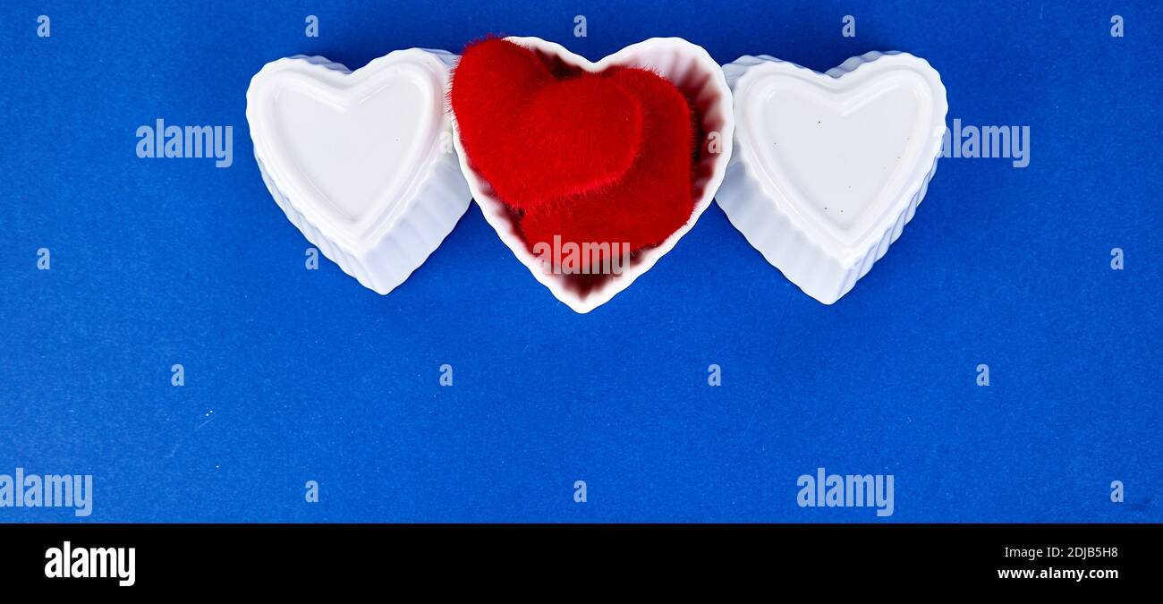 Banner ofWhite ceramic hearts with red plush hearts on blue trend color background. Flat lay composition. Romantic, St Valentines Day concept. Love. C Stock Photo