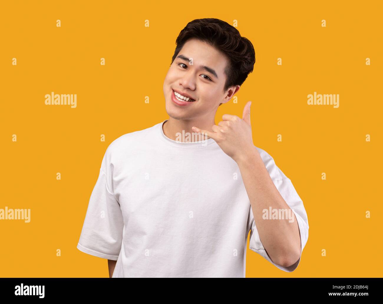 Smiling asian man doing call me phone gesture Stock Photo