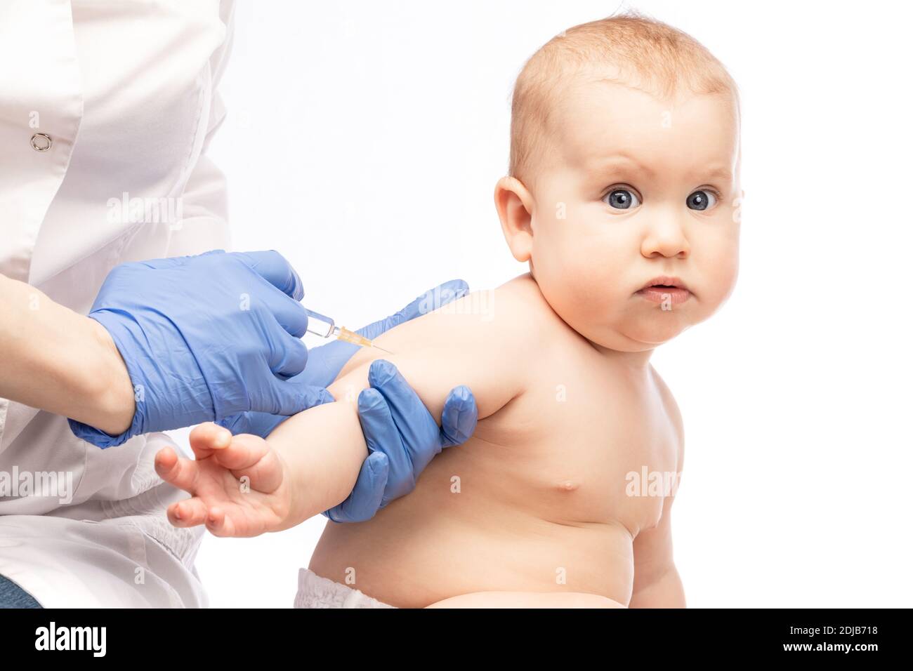 Pediatrician or nurse giving an intramuscular injection of a vaccine to arm of a baby girl during coronavirus COVID-19 pandemic Stock Photo