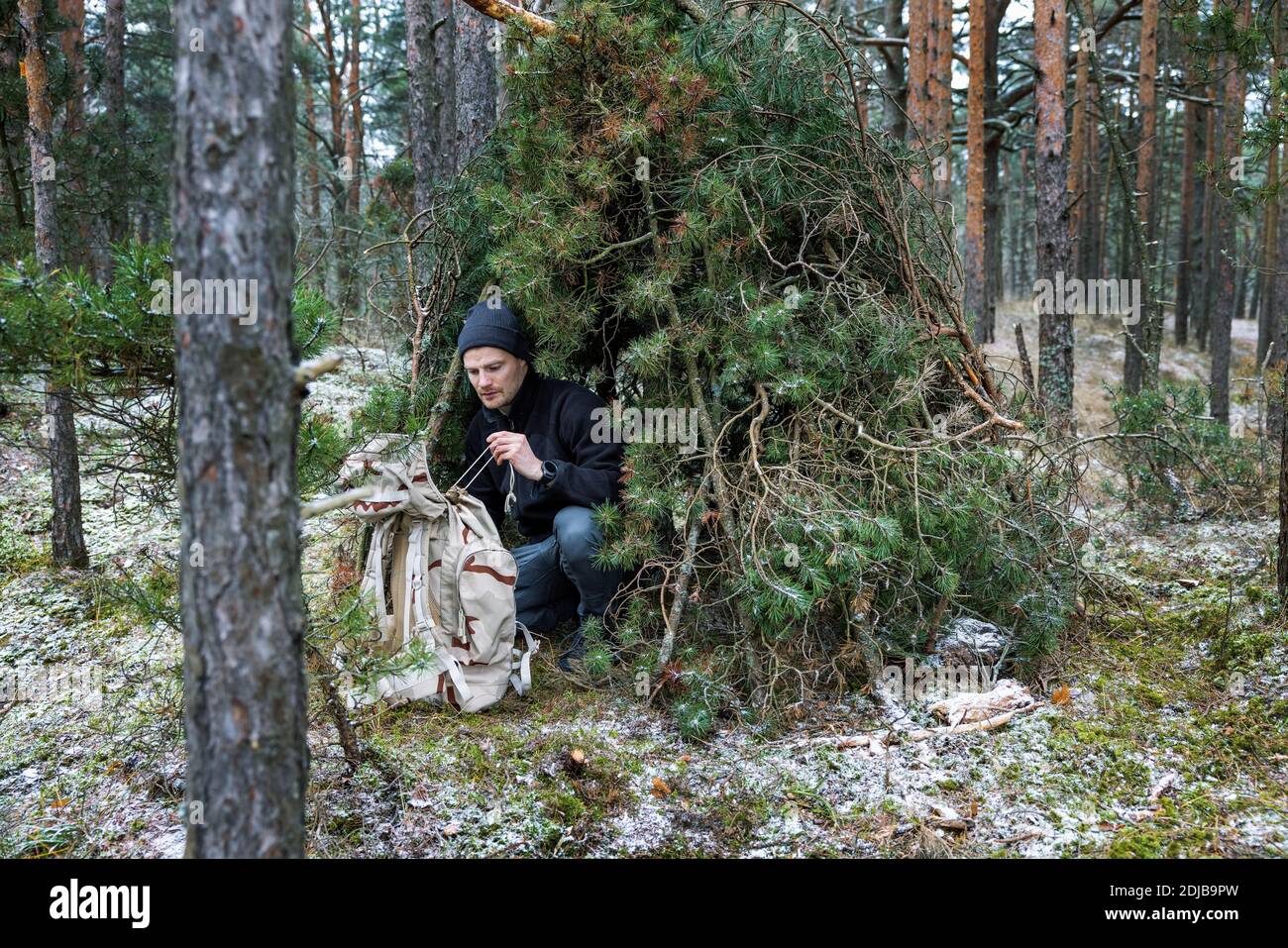 outdoor adventure - man in tree branch shelter into the wild Stock Photo