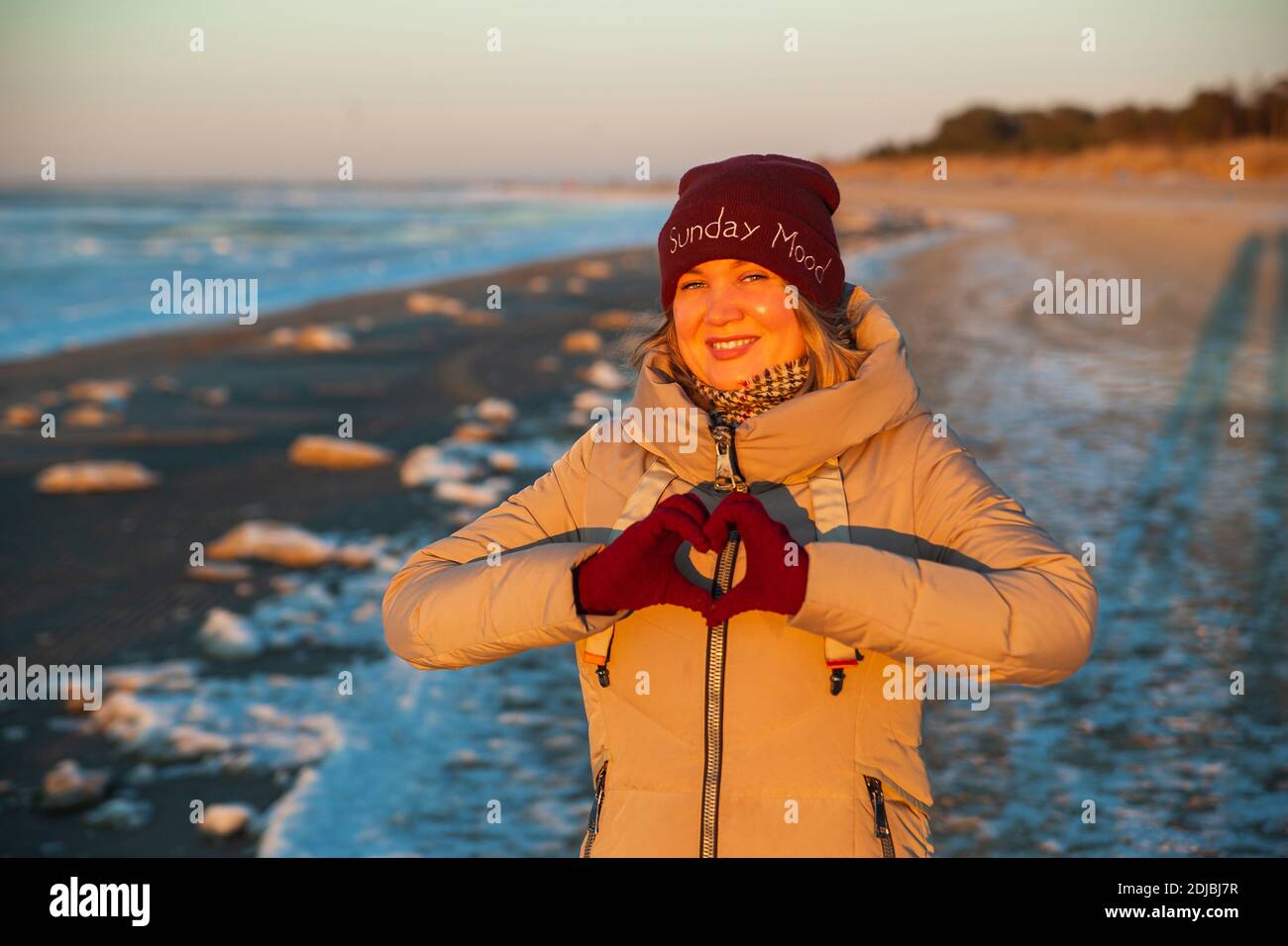 Beutiful Woman hands in red winter gloves Heart symbol shaped Lifestyle, Winter Solstice and Feelings concept with sunset light nature on background. Stock Photo