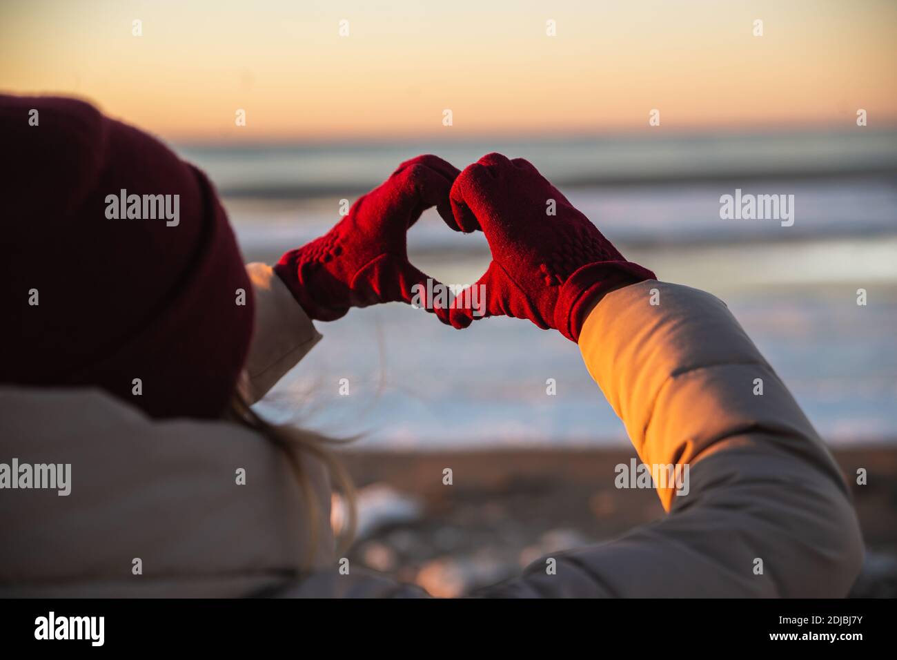 Woman hands in red winter gloves Heart symbol shaped Lifestyle, Winter Solstice and Feelings concept with sunset light nature on background Stock Photo