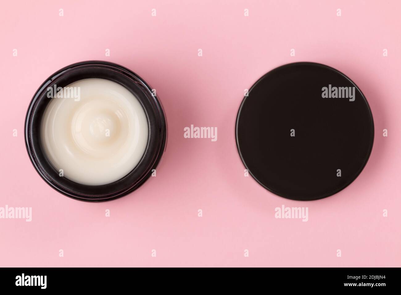 Cosmetic face cream in an open jar on a pink background. Stock Photo