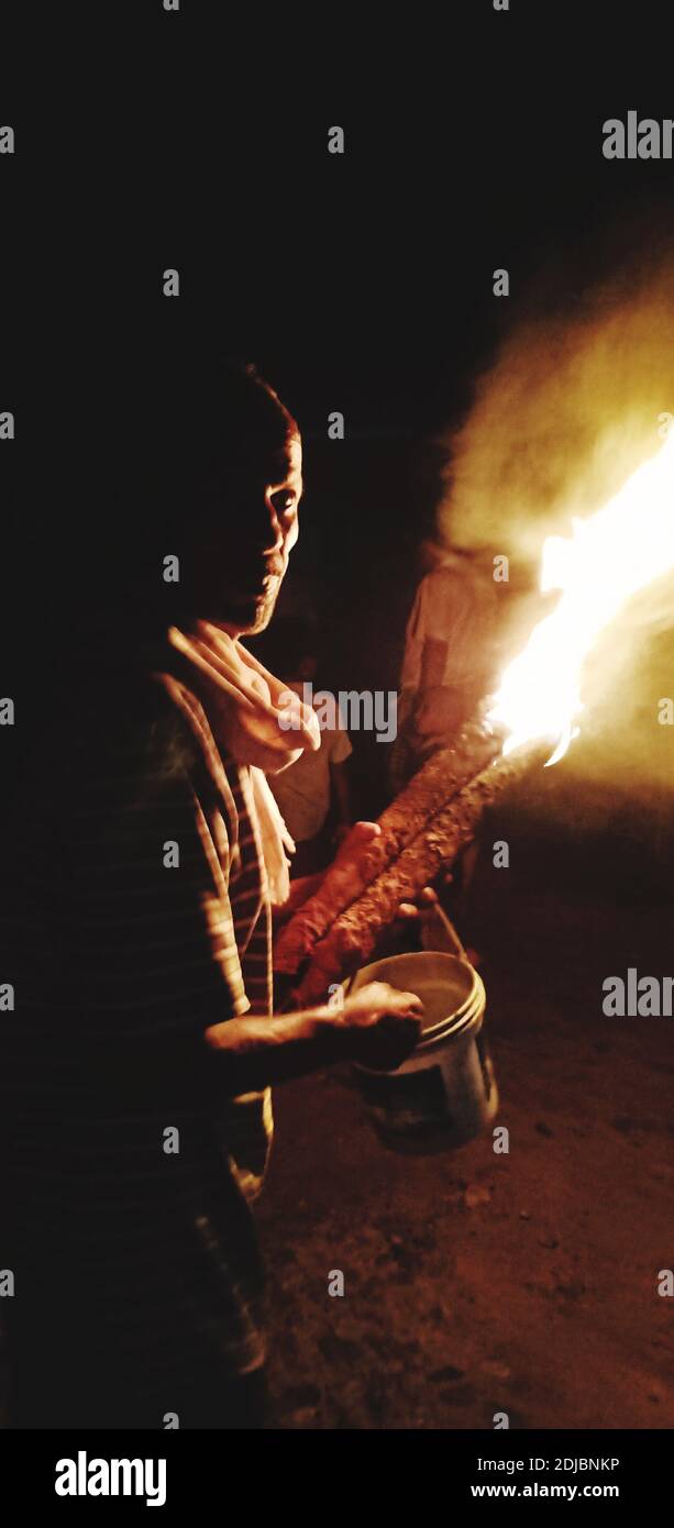 Side View Of Mature Man Holding Fire While Standing Against Sky At Night Stock Photo