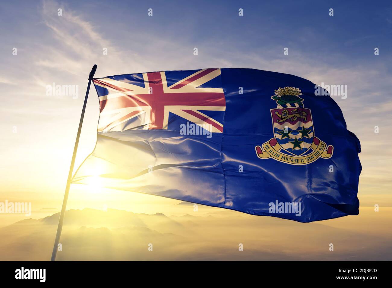 Cayman Islands flag waving on the top sunrise mist fog Stock Photo