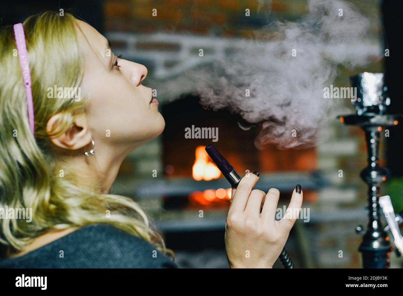 Portrait of a woman smoking hookah. Girl smokes a hookah. Blonde girl