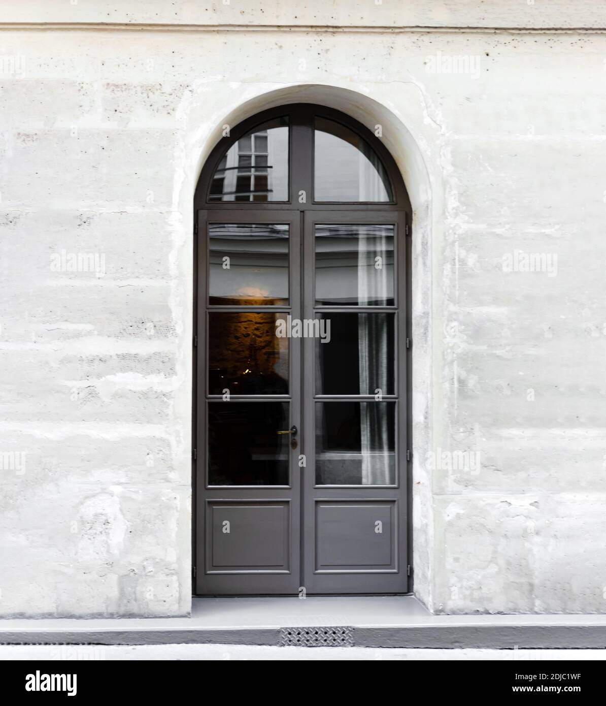 New arched gray wooden double leaf door. Wooden gate - entrance. Vintage old gray door in stone wall in concrete house Paris France. square crop Stock Photo