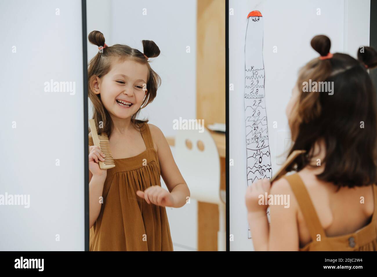 Girl looks after her hair and laughs in front of mirror Stock Photo - Alamy