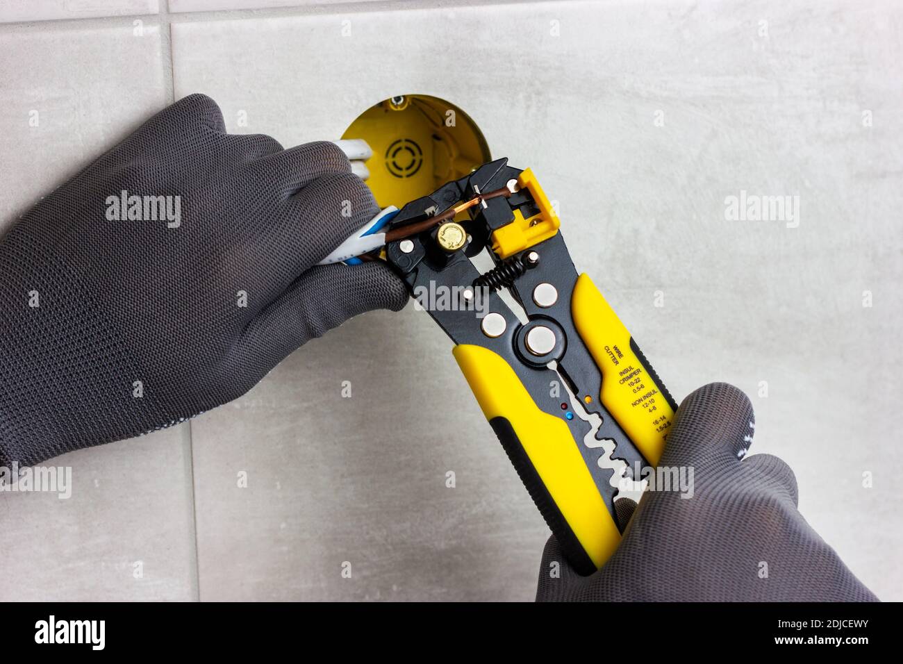 The hands of the master hold the wire cutters and remove the insulation