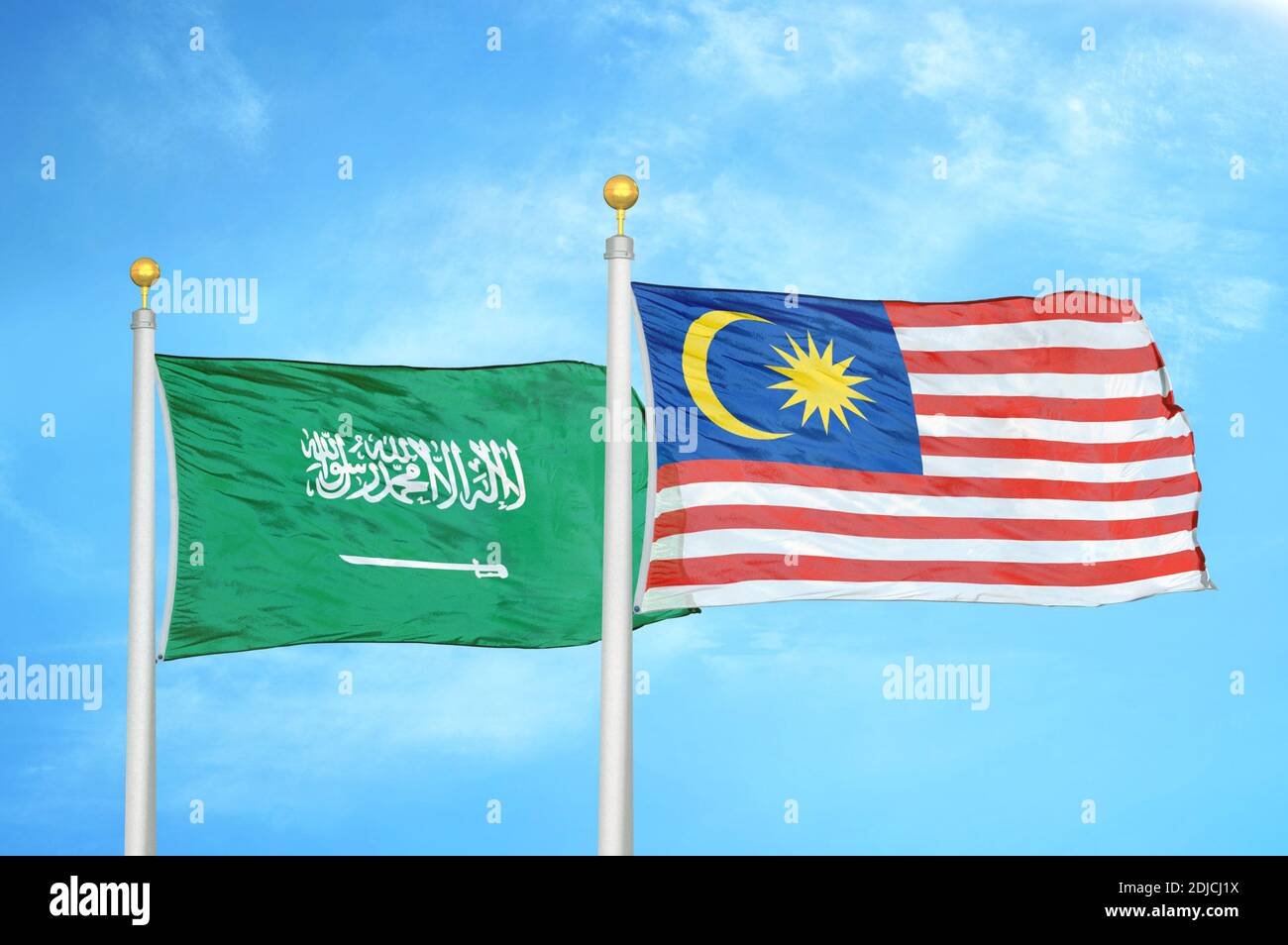 Saudi Arabia and Malaysia two flags on flagpoles and blue cloudy sky Stock Photo
