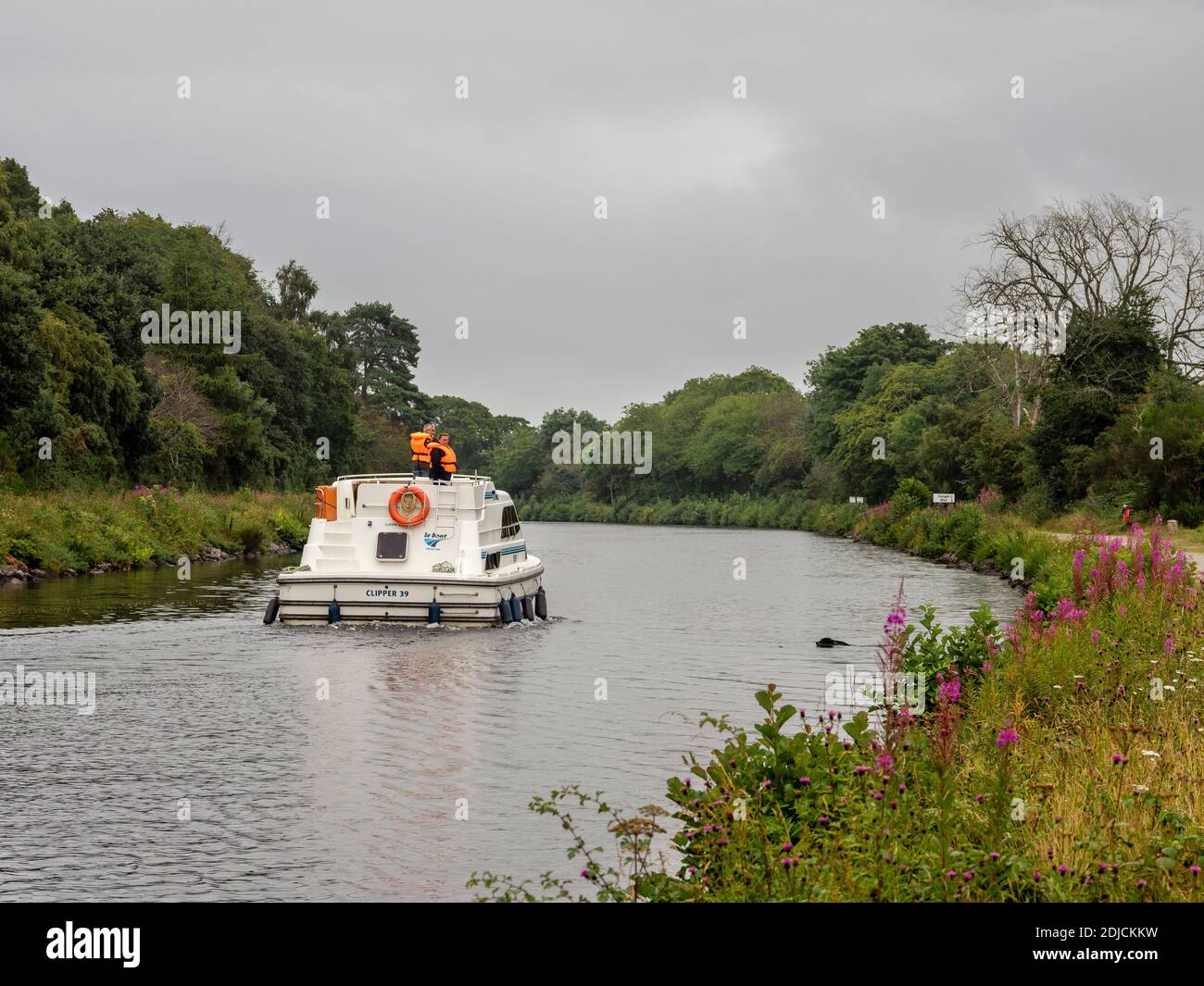 People on a pleasure boat watch a dog retrieving a ball from the Caledonian Canal near Inverness, Highland, Scotland Stock Photo