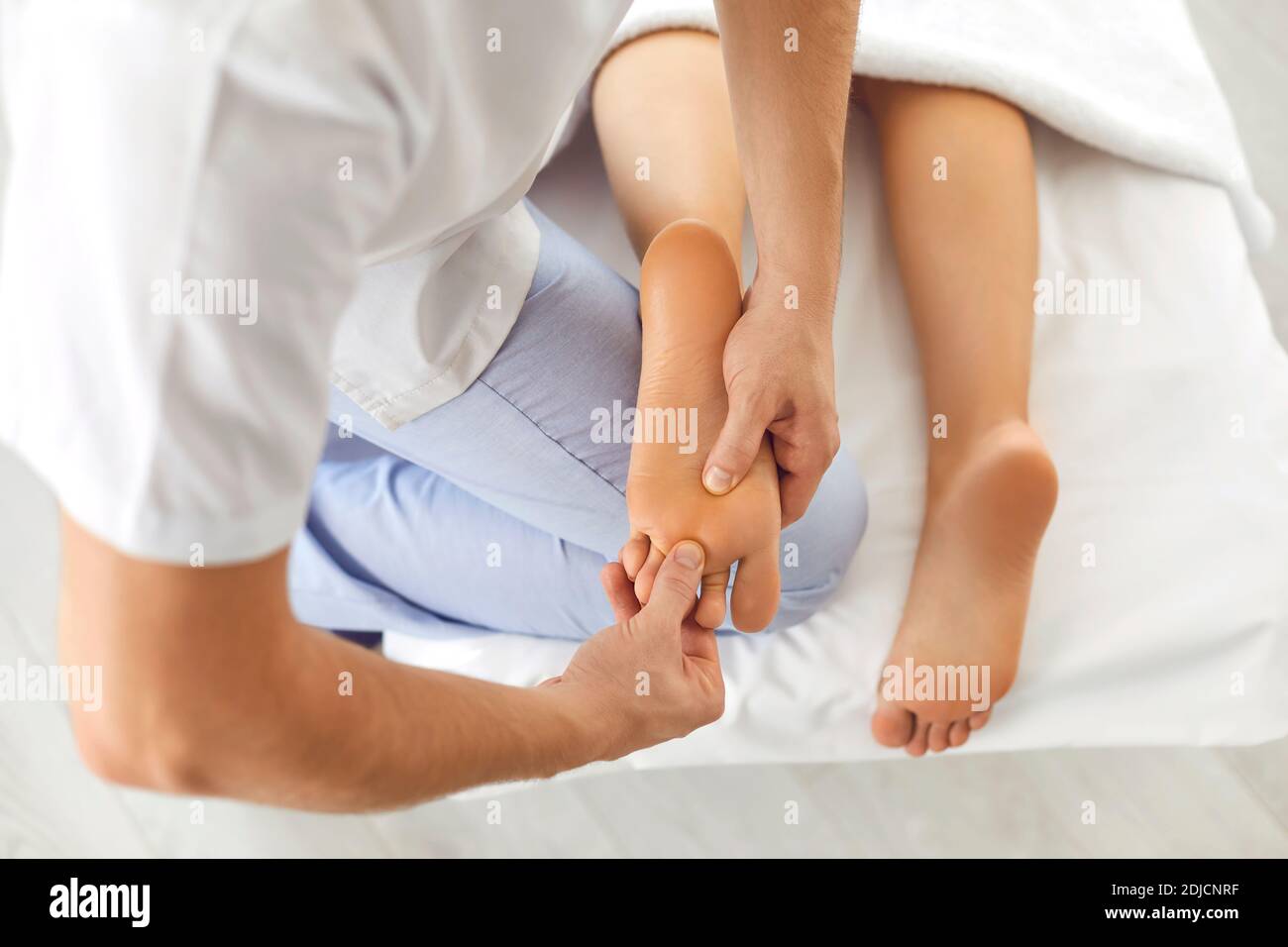 Professional reflexologist doing foot massage for female patient in modern health clinic Stock Photo