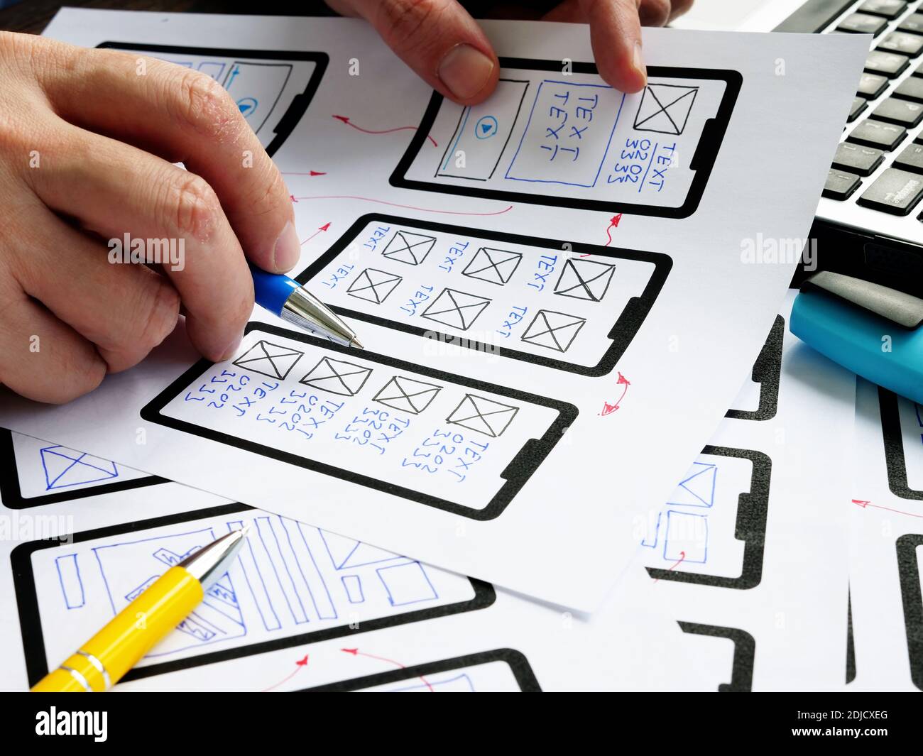 UX designer works with sketches of mobile app and website. Stock Photo