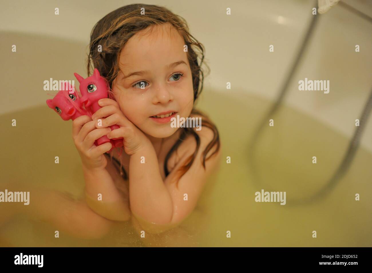 sweet toddler baby girl in bath. Child girl bathes in a white bathtub. Childhood cleanliness