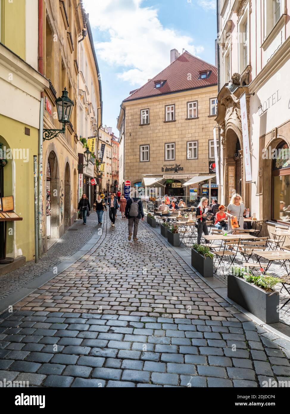 Prague Old Town. A busy urban scene in the narrow cobbled streets of the Czech Republic capital city with shoppers and tourists at a street cafe. Stock Photo