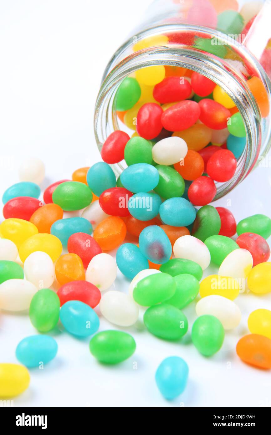 Multi Colored Candies Spilling From Jar Against White Background Stock