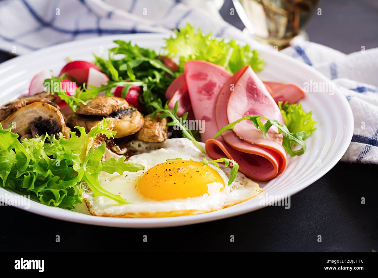 English  breakfast - fried eggs, ham, fried mushrooms, radish and arugula. ketogenic, keto  food. Stock Photo
