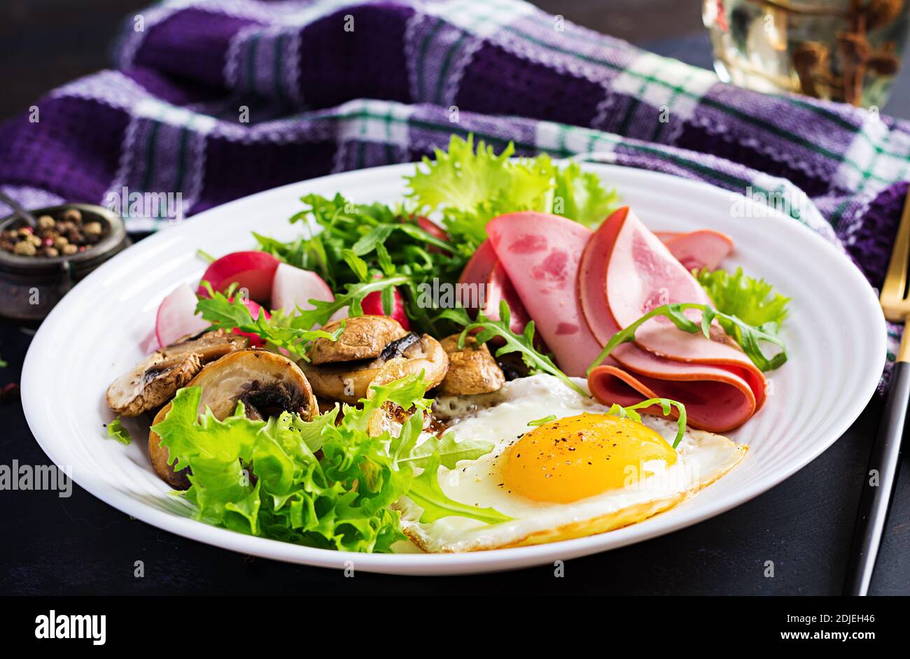 English  breakfast - fried eggs, ham, fried mushrooms, radish and arugula. ketogenic, keto  food. Stock Photo