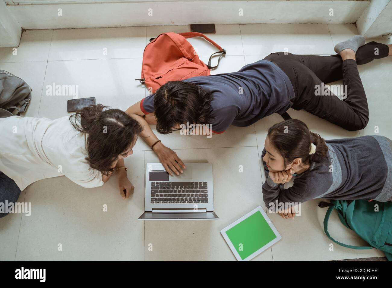 Portrait fun students lying down working in groups on the floor Stock Photo