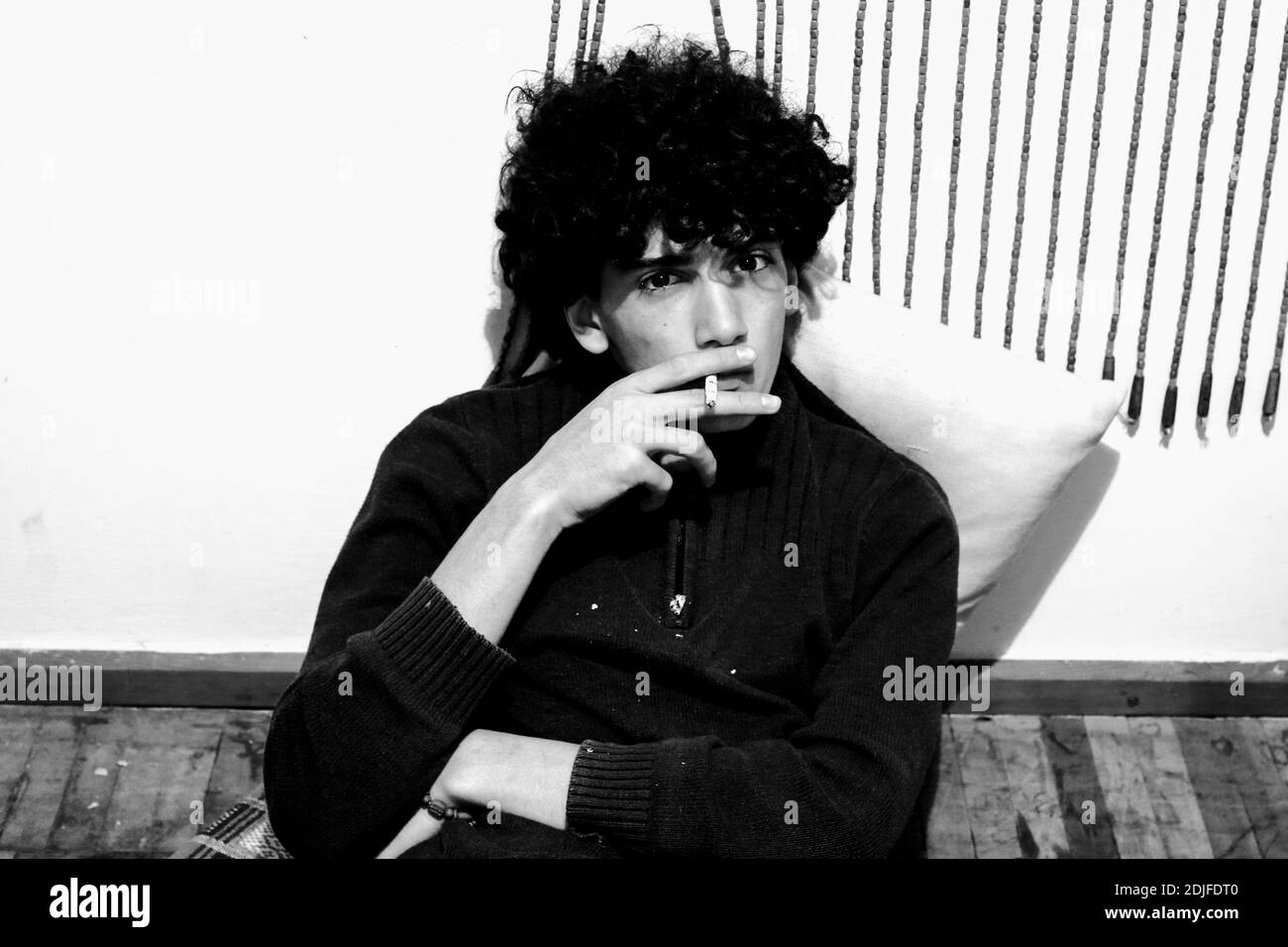 Teenage boy sitting against wall Black and White Stock Photos & Images