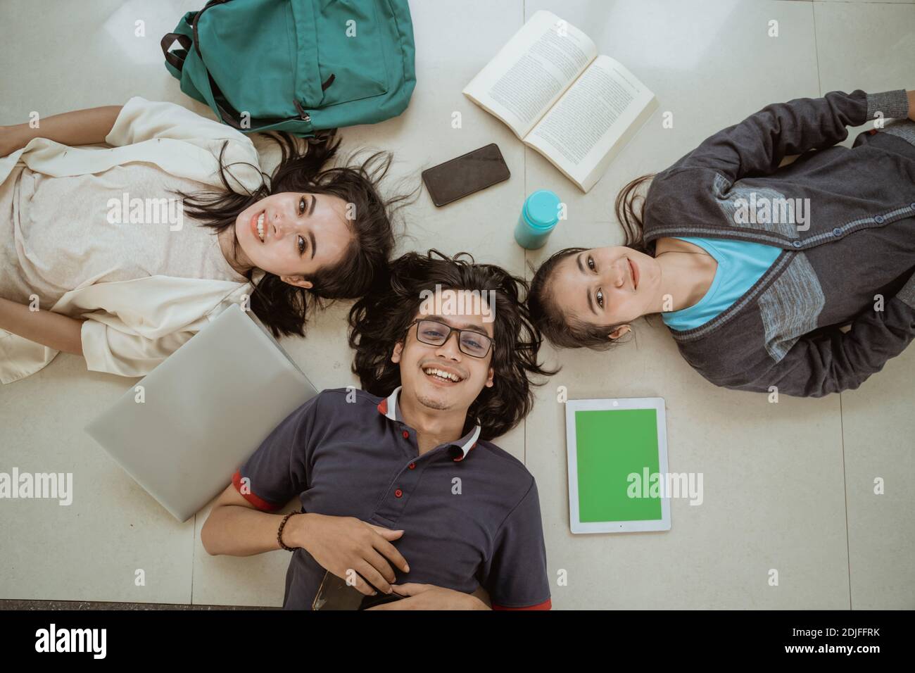 Portrait fun students lying down working in groups on the floor Stock Photo