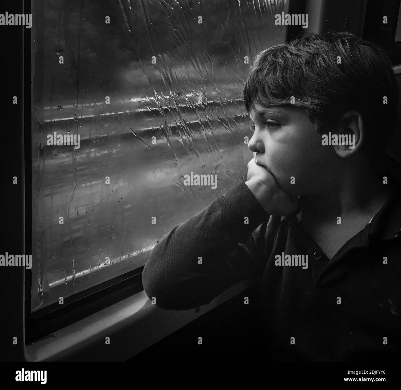 Sad Boy Looking Through Window During Rainy Season Stock Photo - Alamy