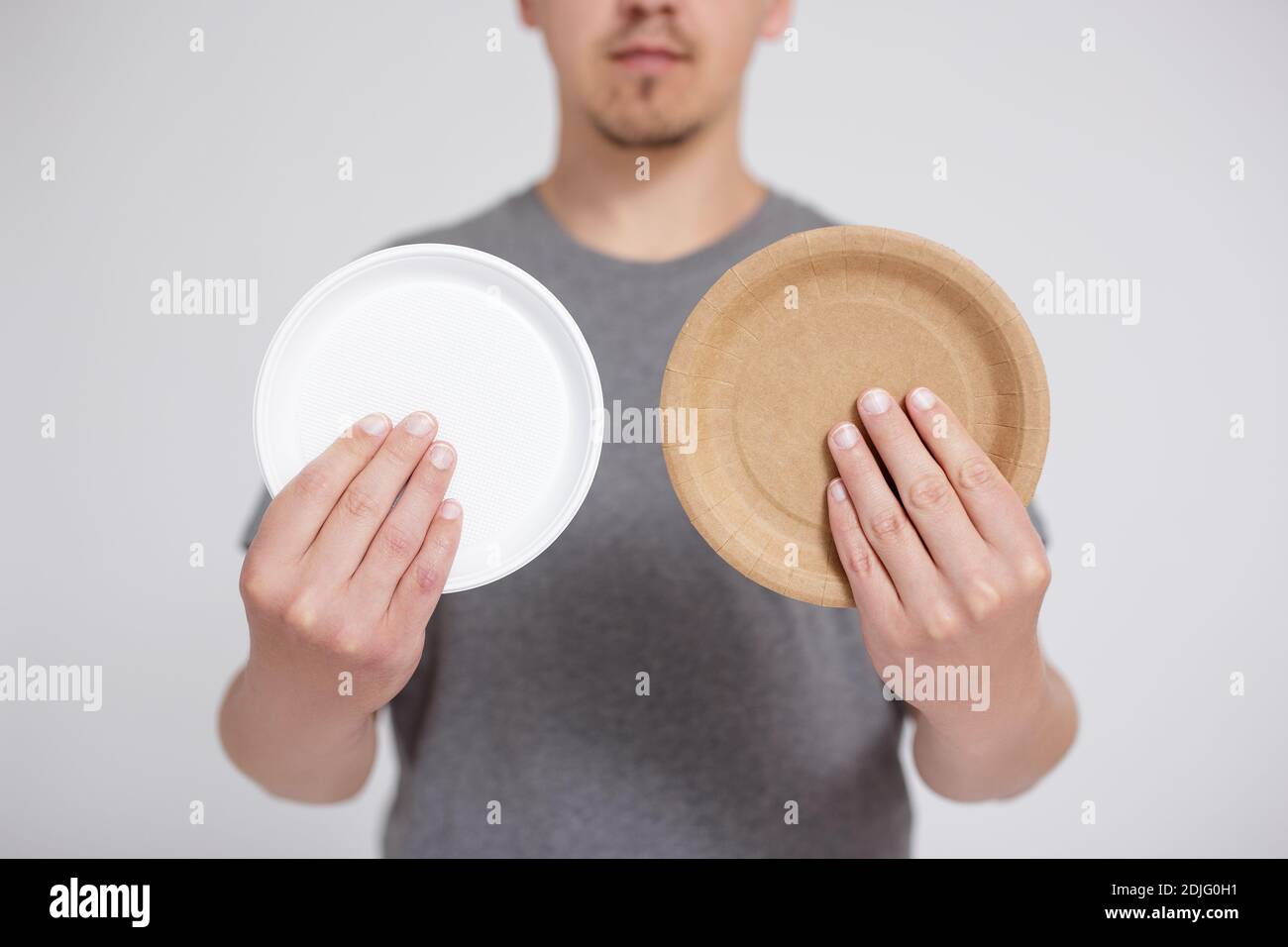 plastic or paper young man choosing between plastic plate and eco