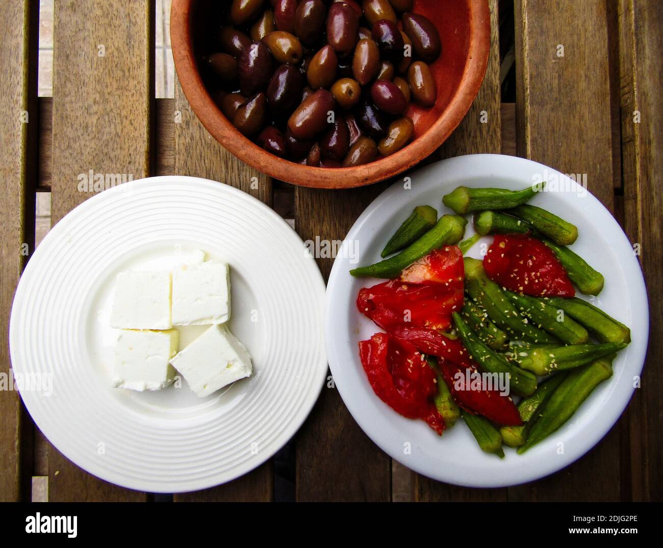 Greek Cuisine. Plates of Olives, Feta Cheese, Okra and Roasted Red Bell Peppers Stock Photo