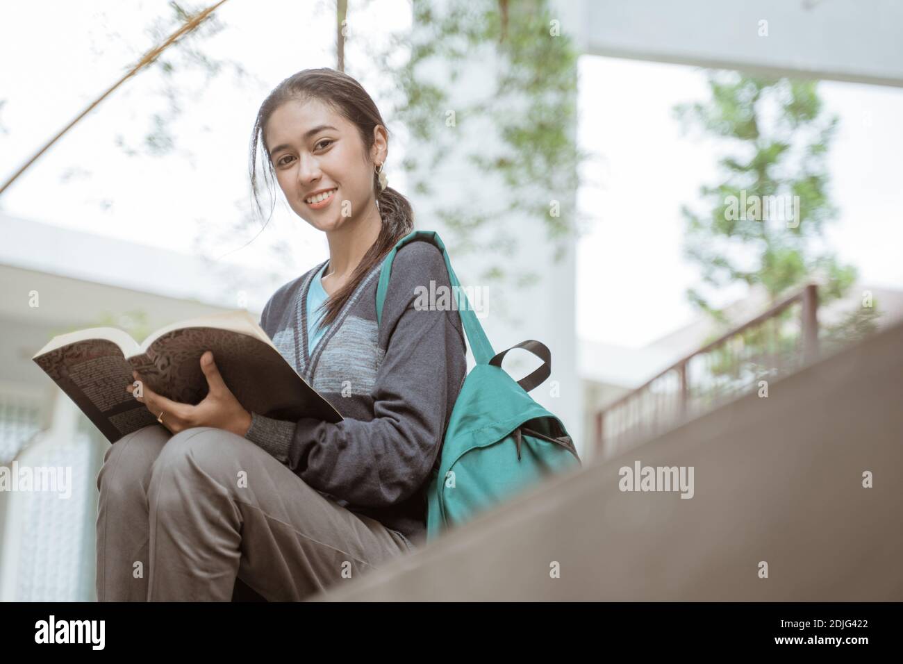 Portrait of happy female student looking camera holding book on the ...