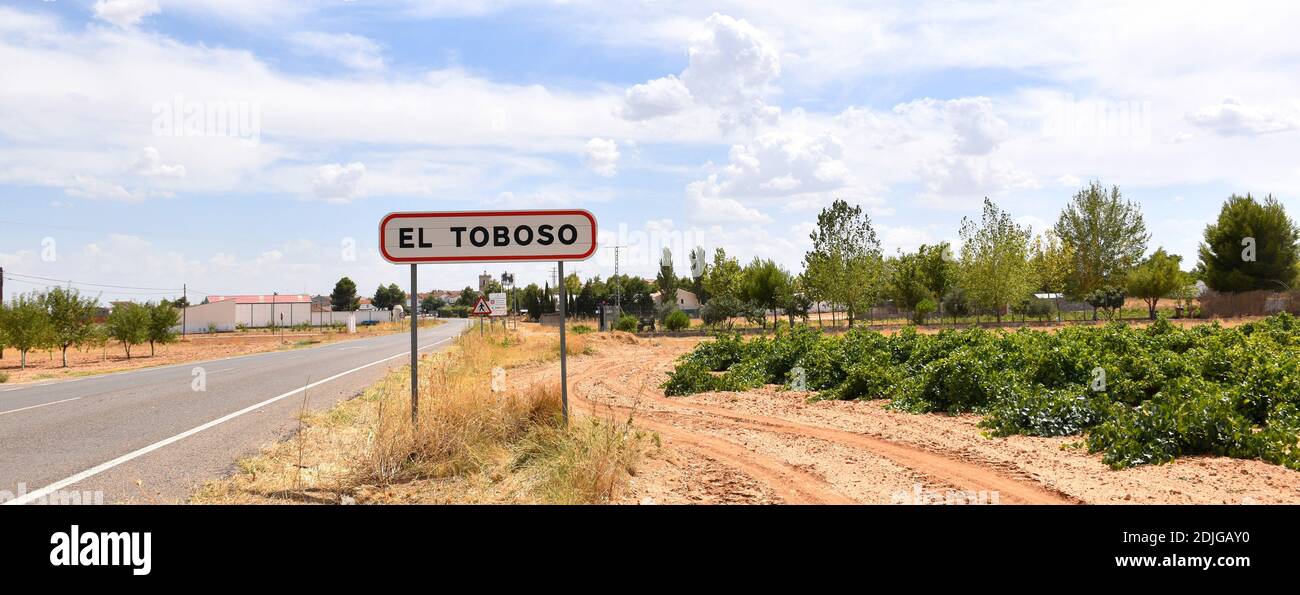 Welcome sign to El Toboso next to the road and vineyards. Stock Photo